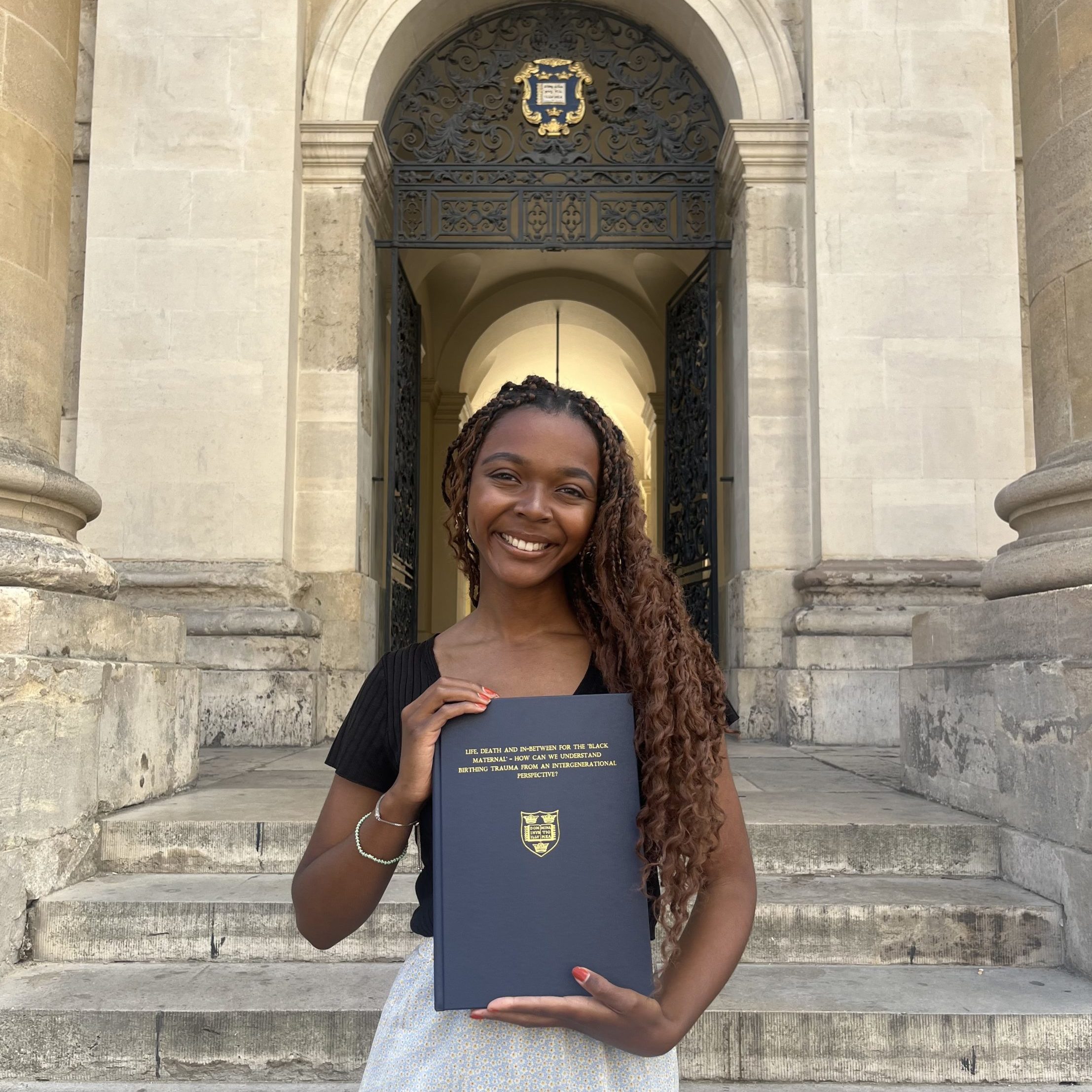 Female student holding a bound, embossed copy of her dissertation.
